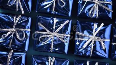 蓝色背景上移动蓝色礼品盒。 圣诞节和新年的旋转背景。 现在，惊喜的概念